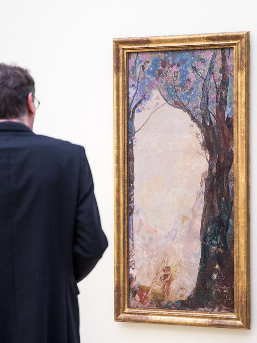 Ein Ausstellungsbesucher steht vor einem Werk von Odilon Redon.
