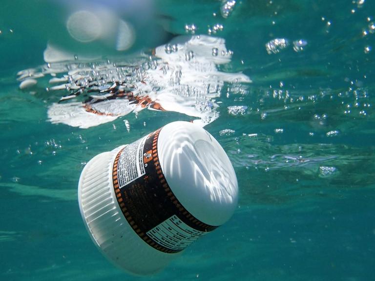 Eine Plastikverpackung treibt unter Wasser im Meer.