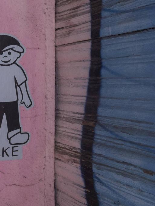 Auf einer Wand ist die stilisierte Figur eines Jungen geklebt. Darunter steht "Icke".
