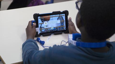 Ein Grundschüler in Marseille mit einem Lernprogramm auf einem Tablet
