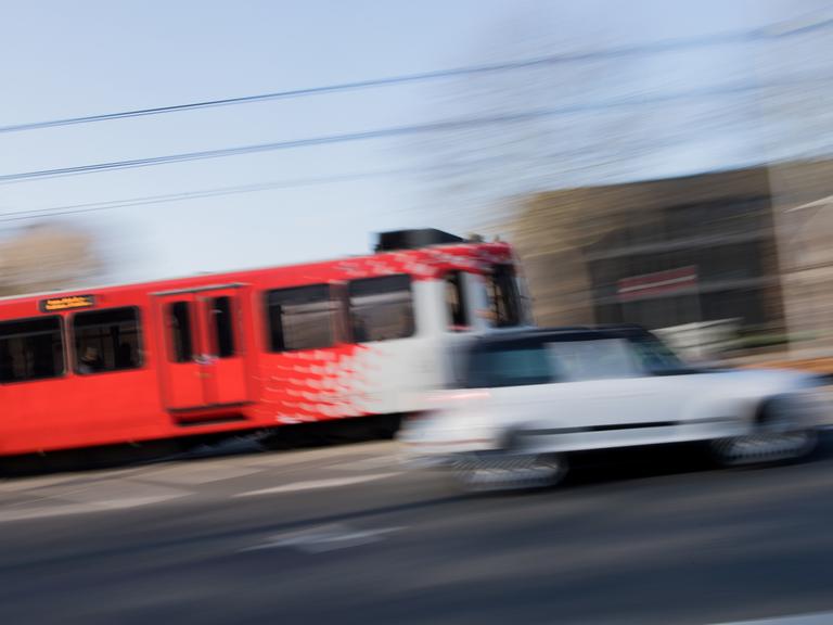 Eine Straßenbahn und ein Auto fahren durch das ehemalige Regierungsviertel in Bonn, Modellstadt für kostenlosen ÖPNV