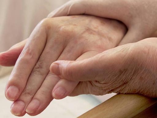 Pflege von Demenzkranken: Ein Paar Hände hält die Hand eines älteren Menschen.