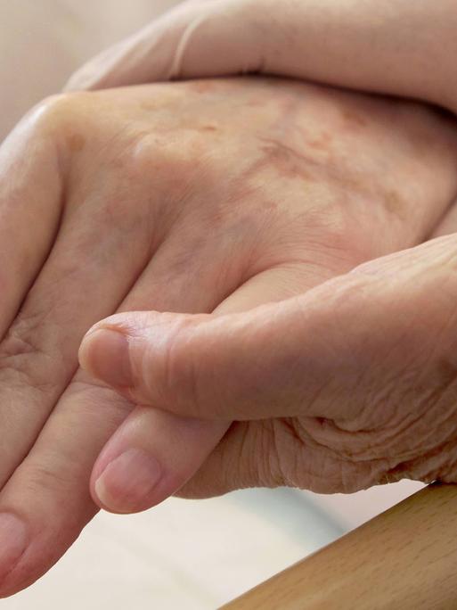 Pflege von Demenzkranken: Ein Paar Hände hält die Hand eines älteren Menschen.