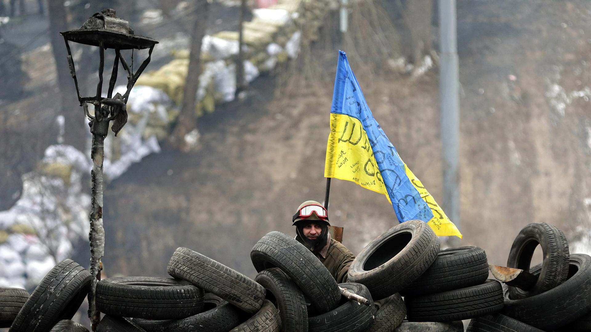 A single protester stands behind a barricade of tires during another day of anti-government protest in Kiev, Ukraine, 28 January 2014. Ukraine's parliament in an extraordinary session on 28 January has repealed a series of laws that have been criticized as stifling dissent and free speech. Ukraine has seen violent protests since November 2013. The demonstrations have been led by pro-Europe activists angry that President Viktor Yanukovych had decided against an association agreement with the European Union in favour of closer relations with Russia.