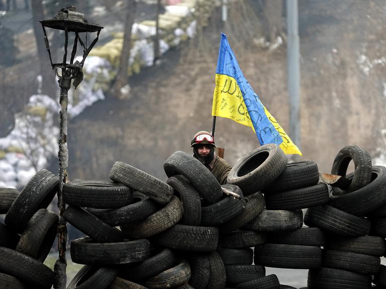 A single protester stands behind a barricade of tires during another day of anti-government protest in Kiev, Ukraine, 28 January 2014. Ukraine's parliament in an extraordinary session on 28 January has repealed a series of laws that have been criticized as stifling dissent and free speech. Ukraine has seen violent protests since November 2013. The demonstrations have been led by pro-Europe activists angry that President Viktor Yanukovych had decided against an association agreement with the European Union in favour of closer relations with Russia.