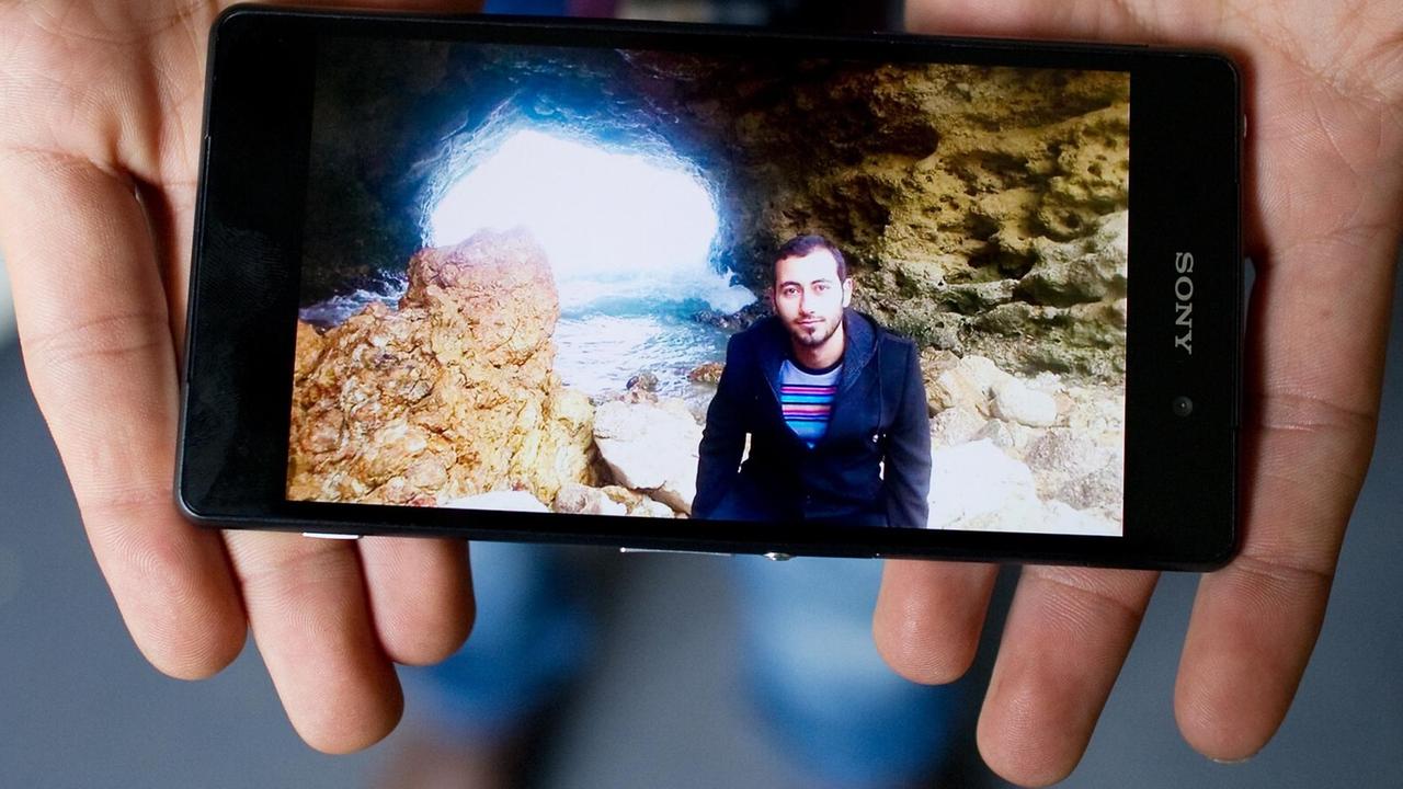 Wajih aus Damaskus in Syrien zeigt  auf seinem Handy ein Foto von seinem Zufluchtsort vor den Kriegswirren am Meer. Auf ihrer Flucht können die Flüchtlinge kaum etwas Persönliches mitnehmen. Meist erinnern nur Fotos auf dem Smartphone an ihr früheres Leben.