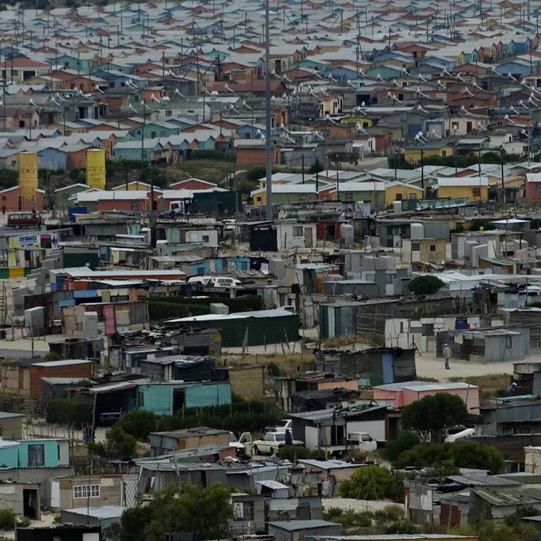 Das Foto zeigt das Viertel "Mitchells Plain" in Kapstadt aus der Luft. Man sieht Wellblechdächer und unzählige Hütten.