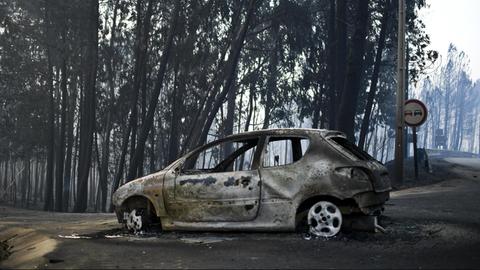 Ausgebranntes Auto auf einer Straße nach dem Waldbrand in Portugal.