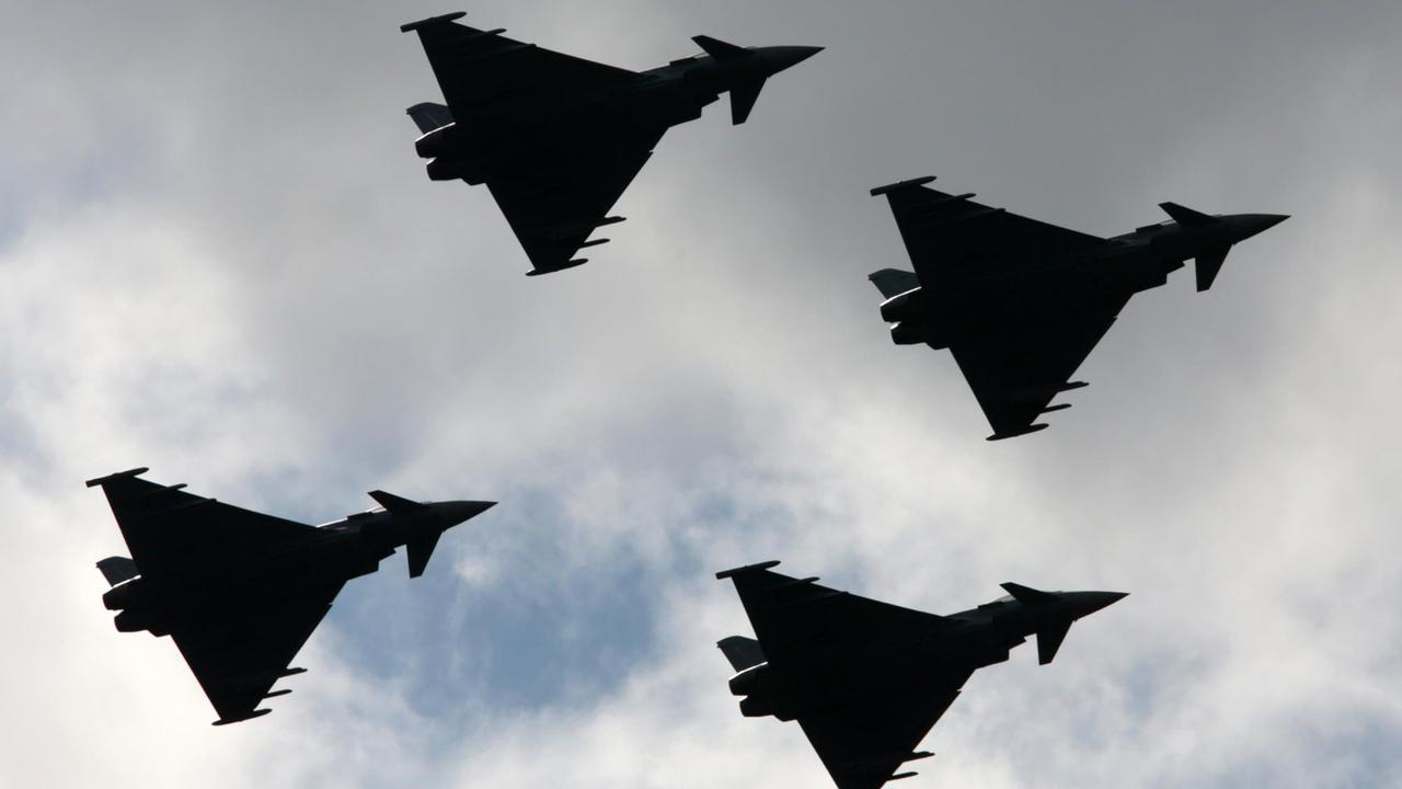 Man sieht die vier Fluzeuge als schwarze Silhouetten von unten am Himmel.