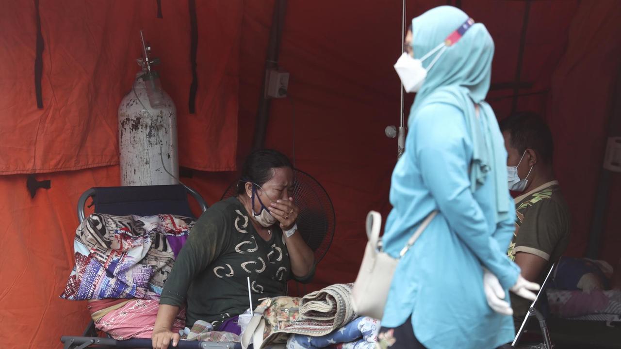 Indonesien, Bekasi: Eine Frau sitzt in einem Notfallzelt, das vor einem Krankenhaus errichtet wurde, um Corona-Patienten unterzubringen.