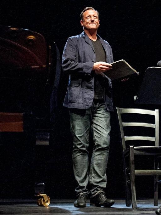 Auf einer Bühne verabschiedet sich der Schauspieler Matthias Brandt von seinem Publikum. Er trägt eine Jeans.