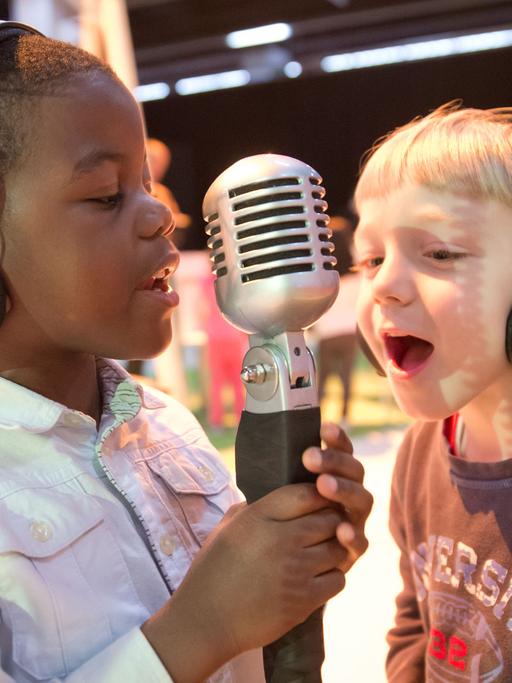 Der sechsjährige Darlington (links) und der gleichaltrige Marvin aus der Frankfurter Kita "Kantapfel" singen am 11.03.2014 in Frankfurt am Main (Hessen) auf der Musikmesse bei der jährlichen Mitmachaktion "music4kids" in ein Mikrofon.