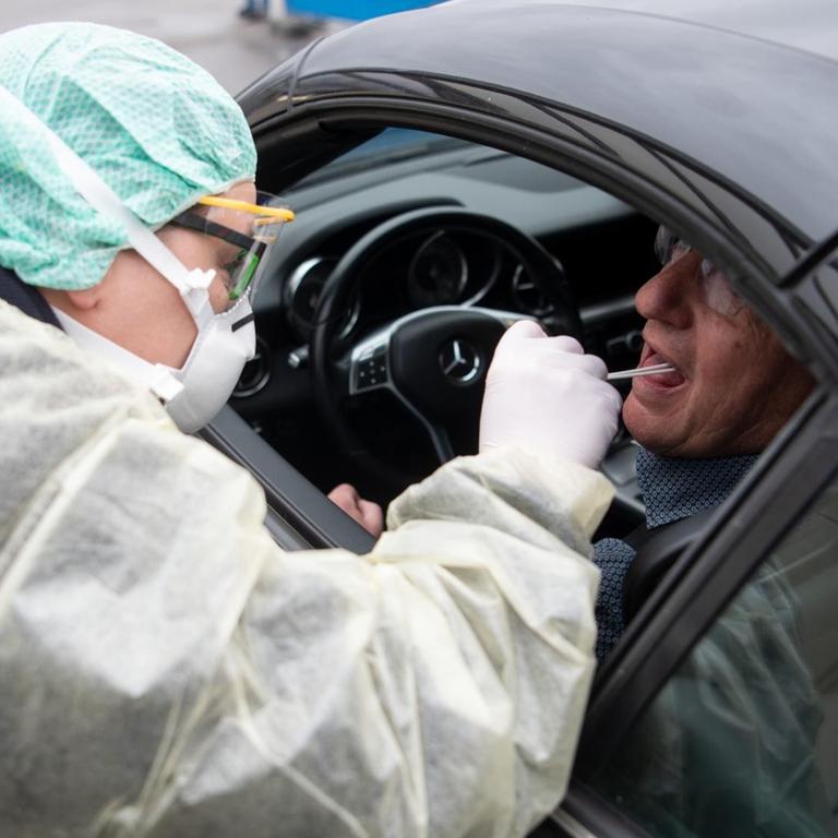 Eine Mitarbeiterin eines Krankenhauses nimmt während eines Pressetermins zum Start einer "Drive-In"-Teststation für den Coronavirus eine Probe durch ein Autofenster.