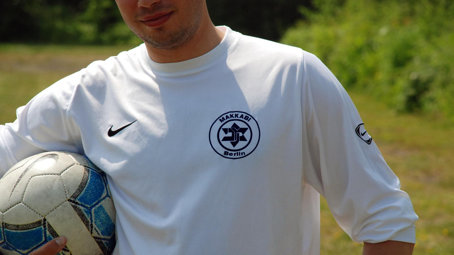 Ein Spieler von TuS Makkabi Berlin steht auf dem Spielfeld und hält den Ball unter dem Arm. Die Weiß-Blauen tragen auf ihrem Trikot einen verfremdeten Davidstern als Vereinswappen. (aufgenommen 2008)
