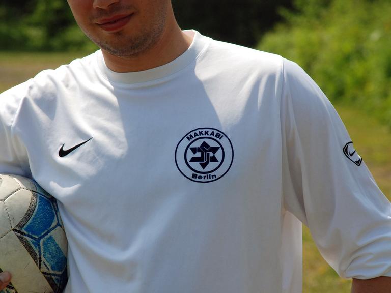 Ein Spieler von TuS Makkabi Berlin steht auf dem Spielfeld und hält den Ball unter dem Arm. Die Weiß-Blauen tragen auf ihrem Trikot einen verfremdeten Davidstern als Vereinswappen. (aufgenommen 2008)