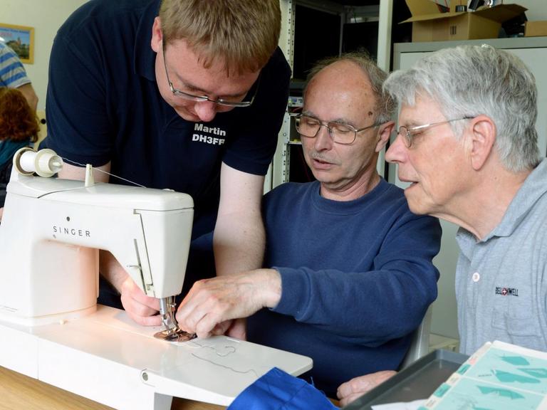 Der Diplom-Ingenieur und leidenschaftliche Bastler Martin Kramer (l) repariert im Repair-Café zusammen mit Johann Schütt (M) eine Nähmaschine von Wolfgang Rogoll.