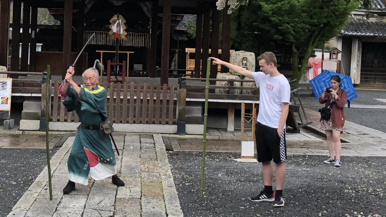 Der 90jährige Joe Okada führt Katana-Schwertkunst-Übungen aus - Besucher schauen zu