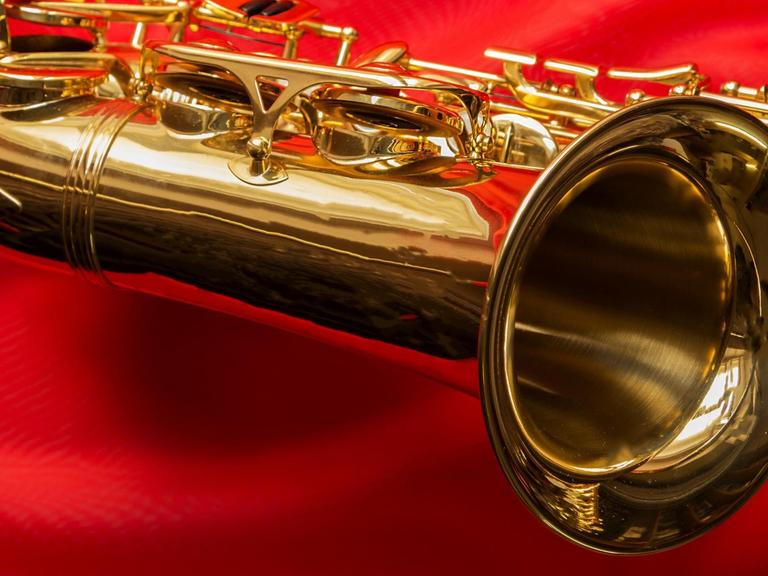 Ein geputztes, golden strahlendes Saxophon liegt auf einem knallrotem Tuch.