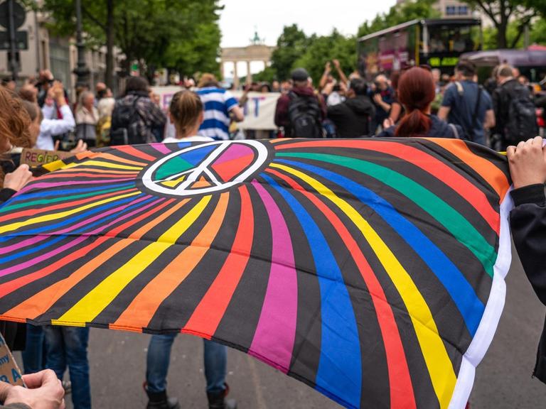 Impression von einer "Hygiene-Demo" in Berlin: Demonstranten halten eine bunte Flagge mit dem Peace-Zeichen.