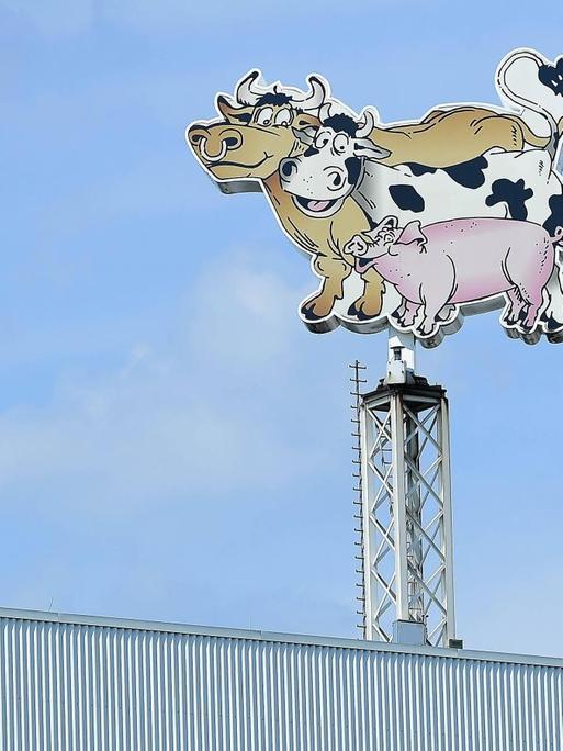 Auf dem Dach des Fleischverarbeiters Tönnies sind an einem Mast ein Bulle, eine Kuh und ein Schwein, deren Schwänze ein Herz bilden, als Werbefiguren abgebildet.