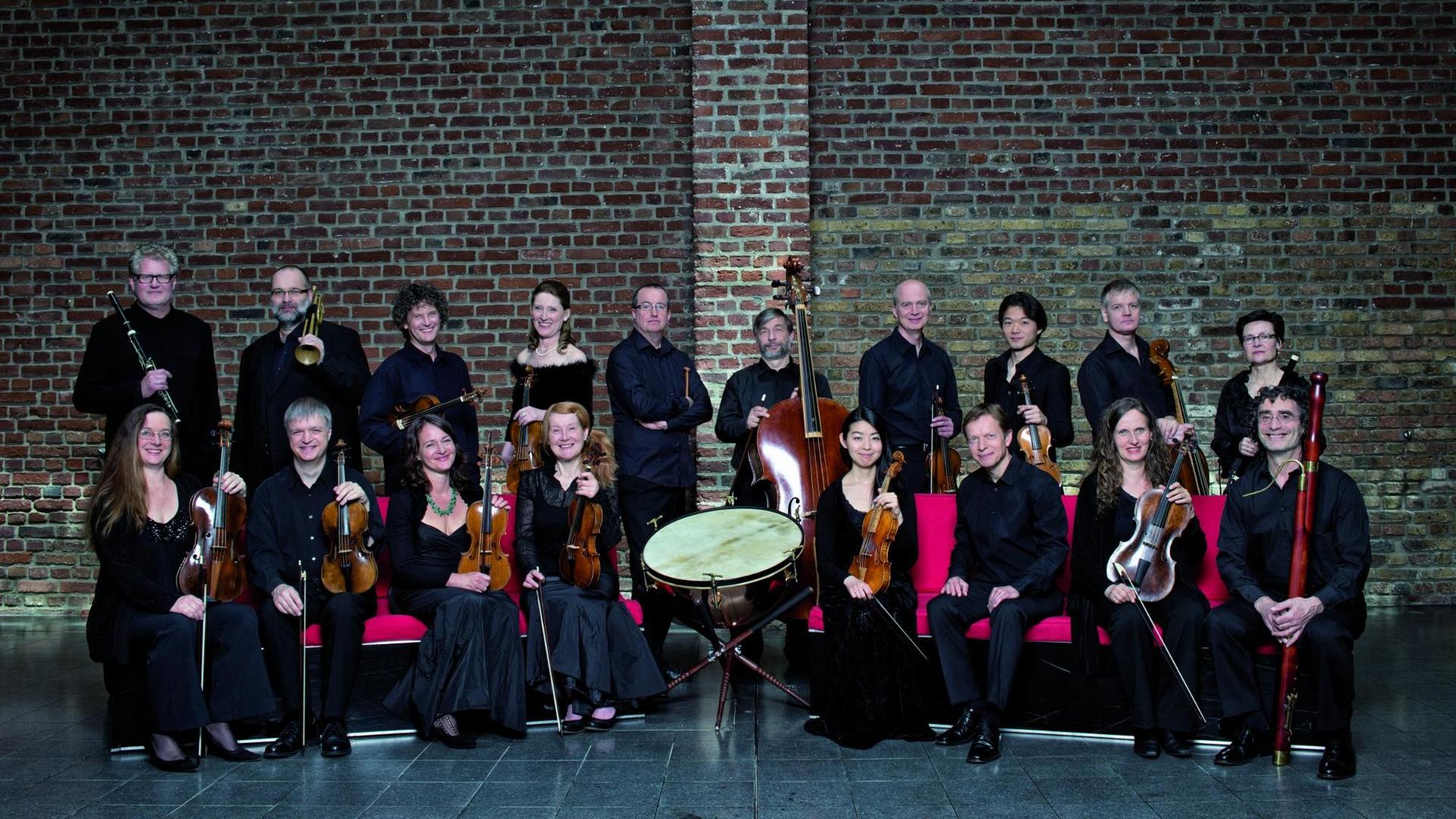 Die Musikerinnen und Musiker des Ensembles Concerto Köln stehen vor einer Backsteinmauer