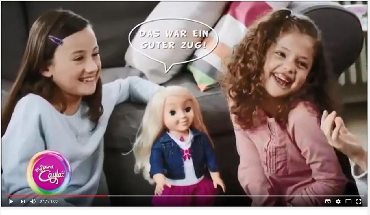 Die Puppe "Cayla" zwischen zwei lachenden Mädchen und der Sprechblase "Das war ein guter Zug!"