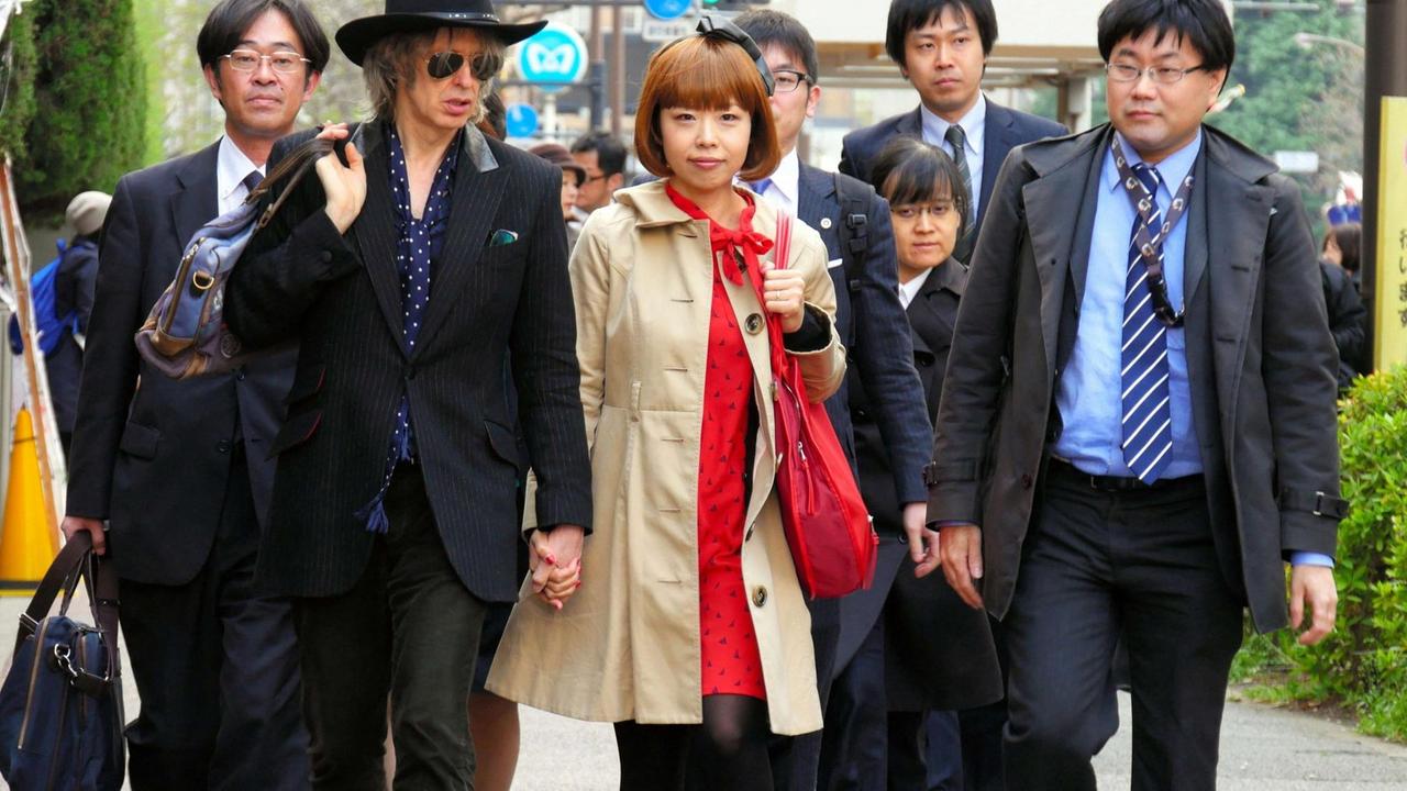 Die Manga-Künstlerin Rokudenashiko läuft in einer Gruppe von Männern und Frauen eine Strasse hinunter.