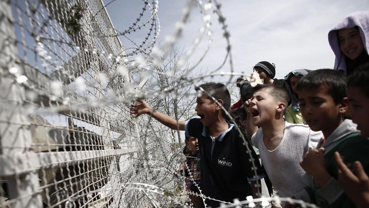 Flüchtlingskinder an einem mit Stacheldraht ausgestatteten Zaun an der griechisch-mazedonischen Grenze im Lager Idomeni.