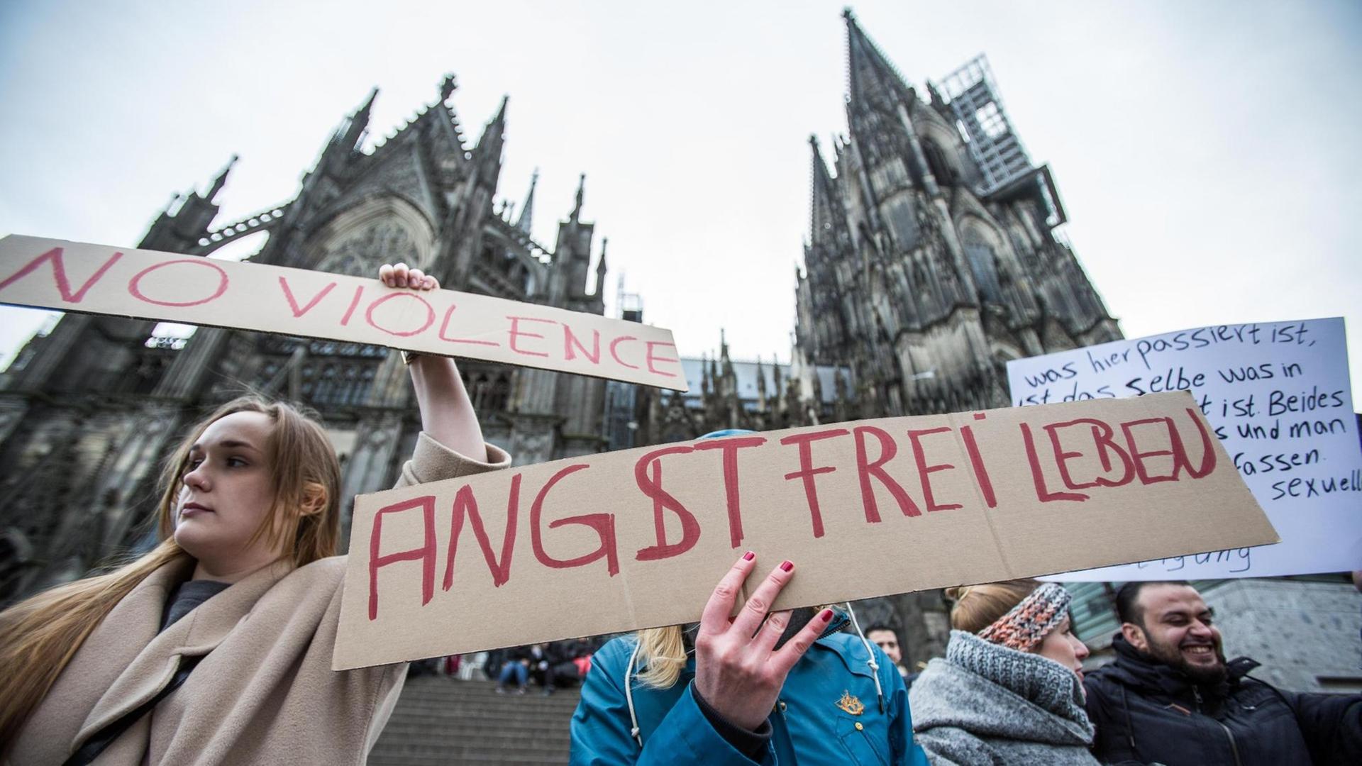 Eine Frau protestiert am 10.01.2016 in Köln vor dem Hauptbahnhof und dem Dom gegen sexuelle Gewalt mit einem Plakat "Angstfrei leben".