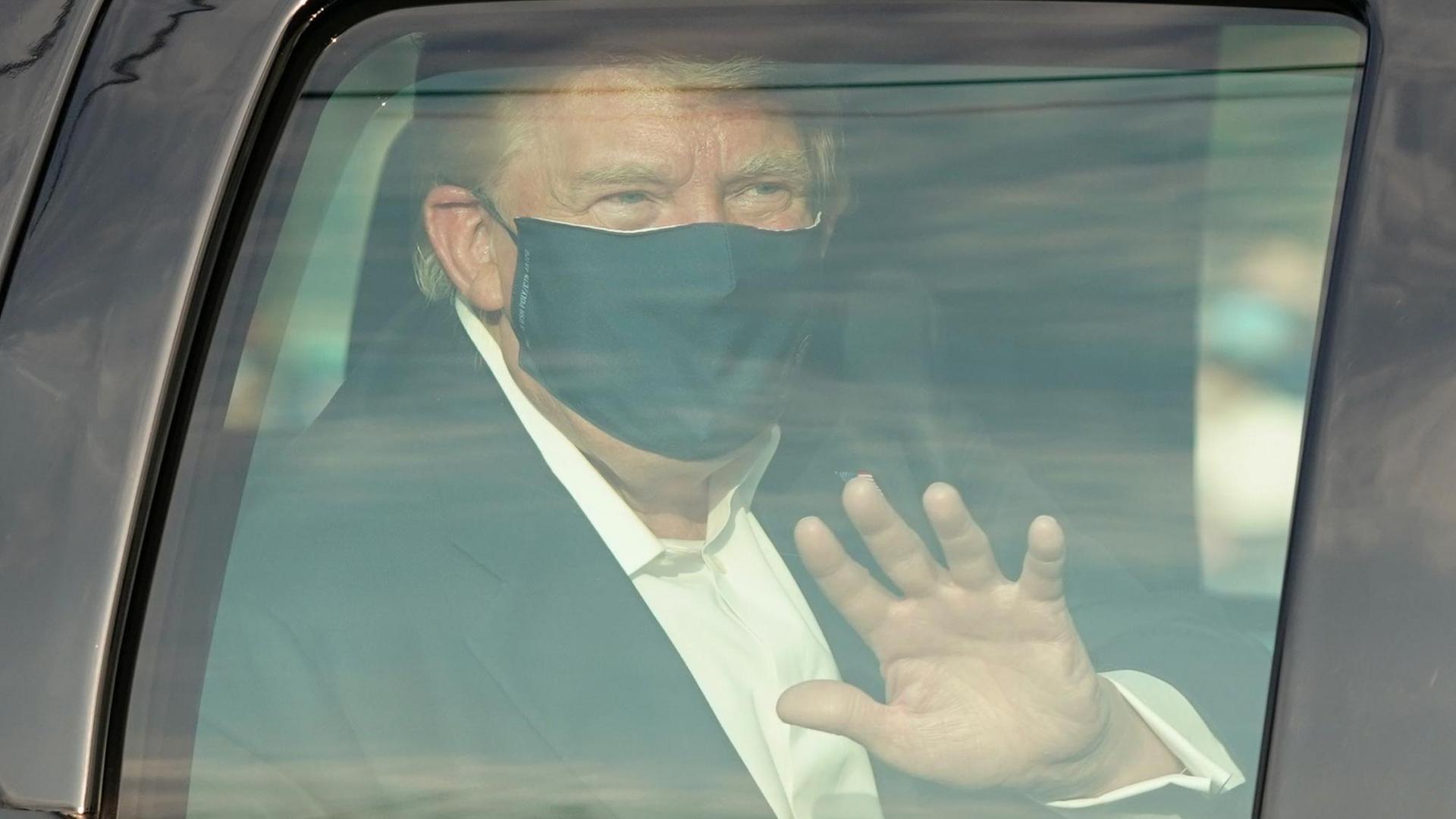 Präsident Trump mit Mundschutz winkt aus seiner Limousine.