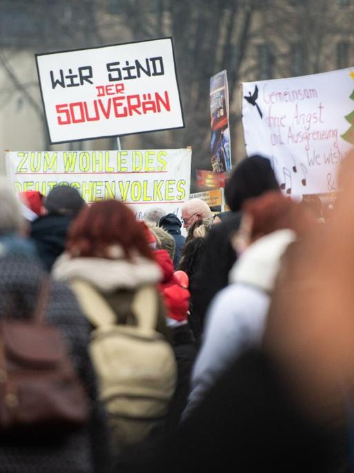 Demonstranten halten bei einer Demonstration am Rheinufer ein Schild mit der Aufschrift „Wir sind der souverän“ in die Höhe. Die Anhänger der «Querdenken»-Initiative hatten zu einer Demonstration gegen die Corona-Maßnahmen auf den Rheinwiesen aufgerufen.