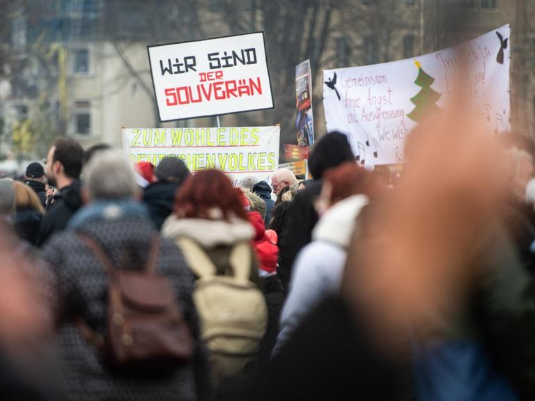 Demonstranten halten bei einer Demonstration am Rheinufer ein Schild mit der Aufschrift „Wir sind der souverän“ in die Höhe. Die Anhänger der «Querdenken»-Initiative hatten zu einer Demonstration gegen die Corona-Maßnahmen auf den Rheinwiesen aufgerufen.
