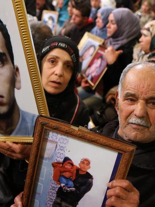 Tunesische Frauen und Männer halten bei einer Demonstration Bilder ihrer Kinder hoch, die während der tunesischen Revoluition gestorben sind.