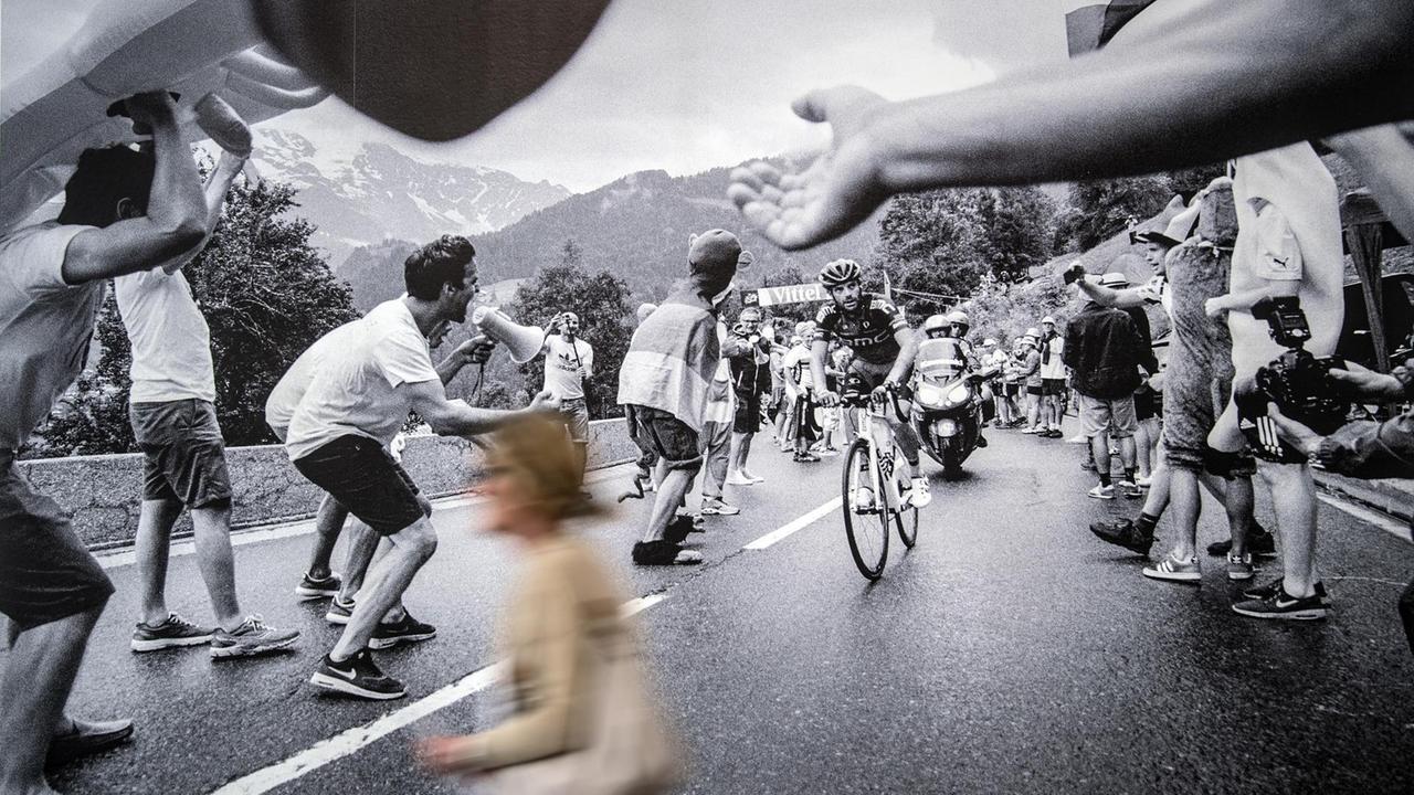Ein Besucher geht in der Foto-Gruppenausstellung "Mythos Tour de France" an einem Bild von Nicola Mesken vorbei.