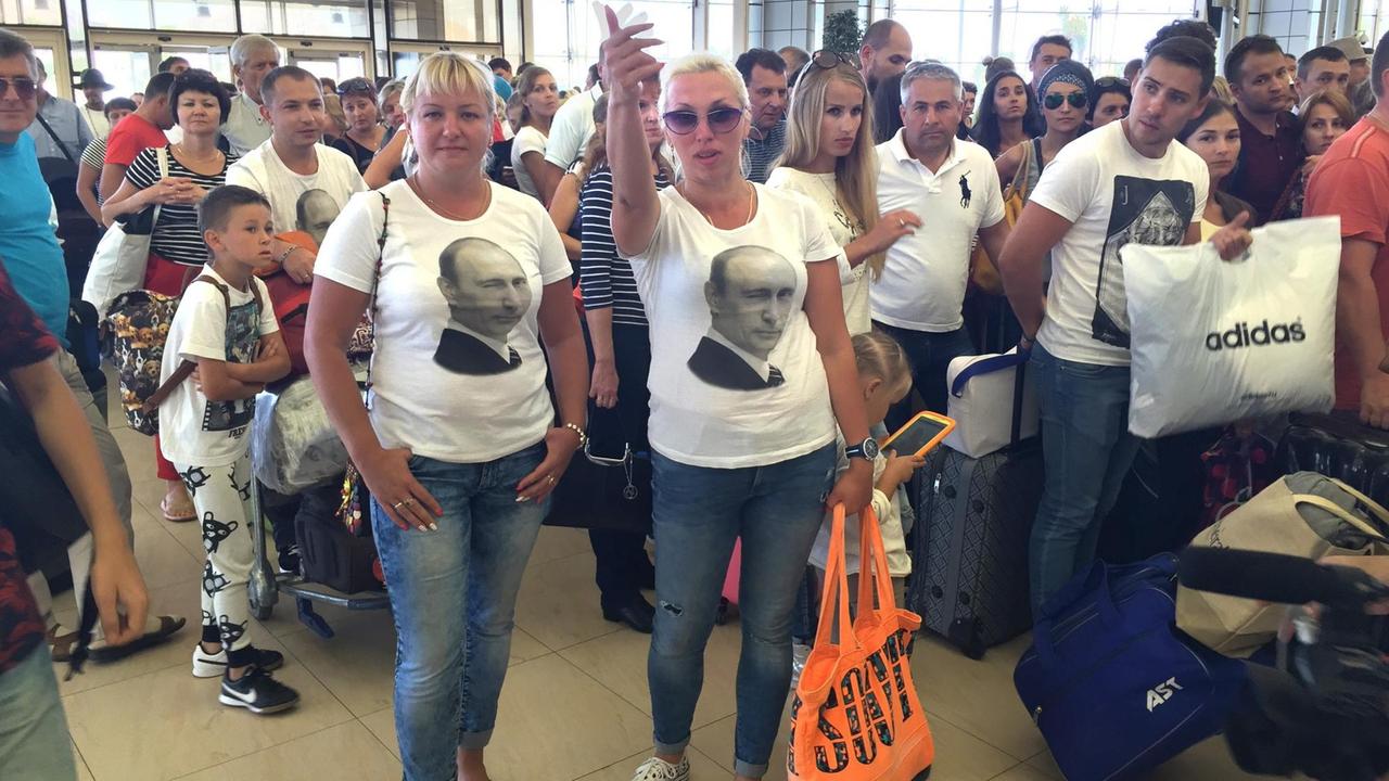 Russische Touristen am Flughafen mit Putin-T-Shirt