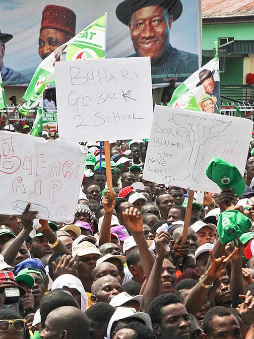 Eine Menschenmenge mit Plakaten, im Hintergrund eine große Werbung für Präsident Goodluck Jonathan.
