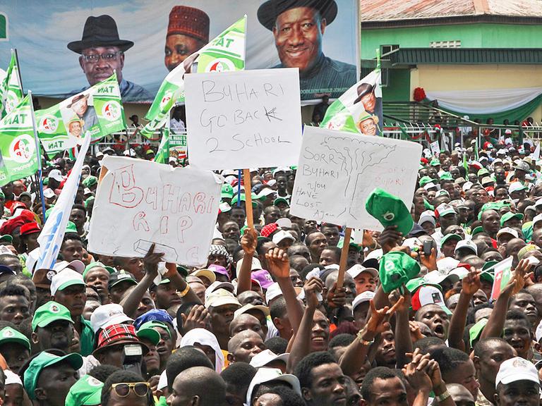 Eine Menschenmenge mit Plakaten, im Hintergrund eine große Werbung für Präsident Goodluck Jonathan.