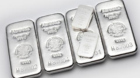 Kleine Silberbarren mit dem Gewicht von einer Unze liegen auf Barren mit dem Gewicht von 1000 Gramm.