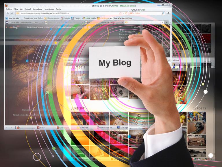 Ein Hand hält ein Schild auf dem "My Blog" steht vor einem Bildschirm. 