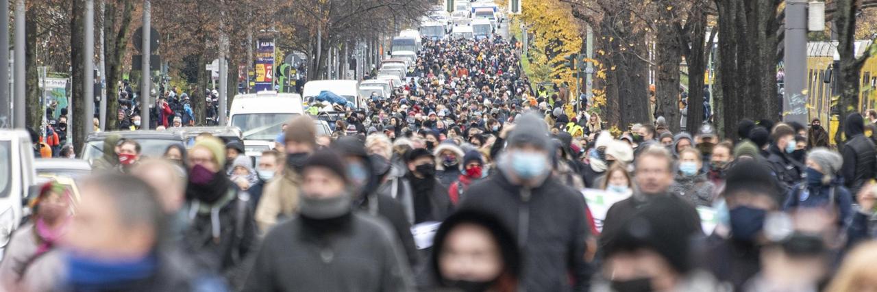 Teilnehmer des Protestzugs gegen die Corona-Politik gehen die Bornholmer Straße in Berlin entlang.