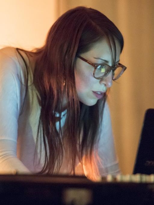 Die Klangkünstlerin Sol Rezza arbeitet an einem Laptop und schaut auf den Bildschirm. Im Vordergrund steht ein Plattenspieler.