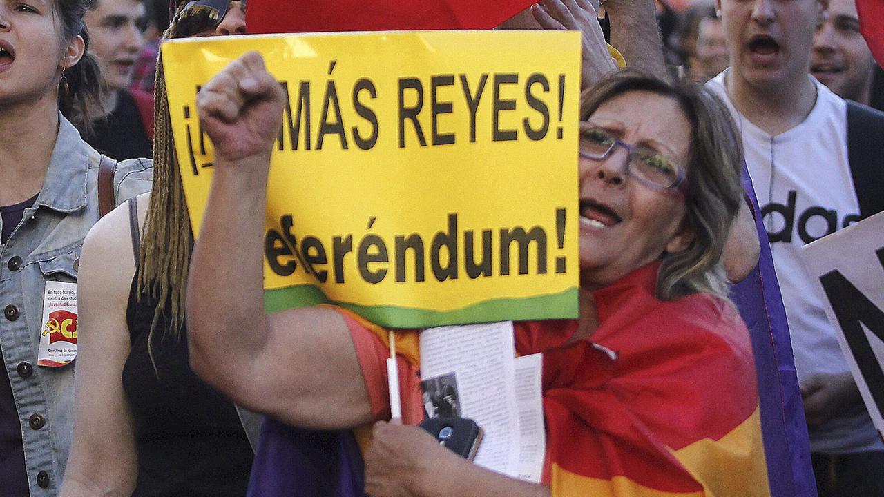 Menschen demonstrieren auf Spaniens Straßen. In der Mitte steht eine Frau mit einer Fahne um den Körper geschlungen und einem Plakat in der Hand, auf dem "Referendum" steht.