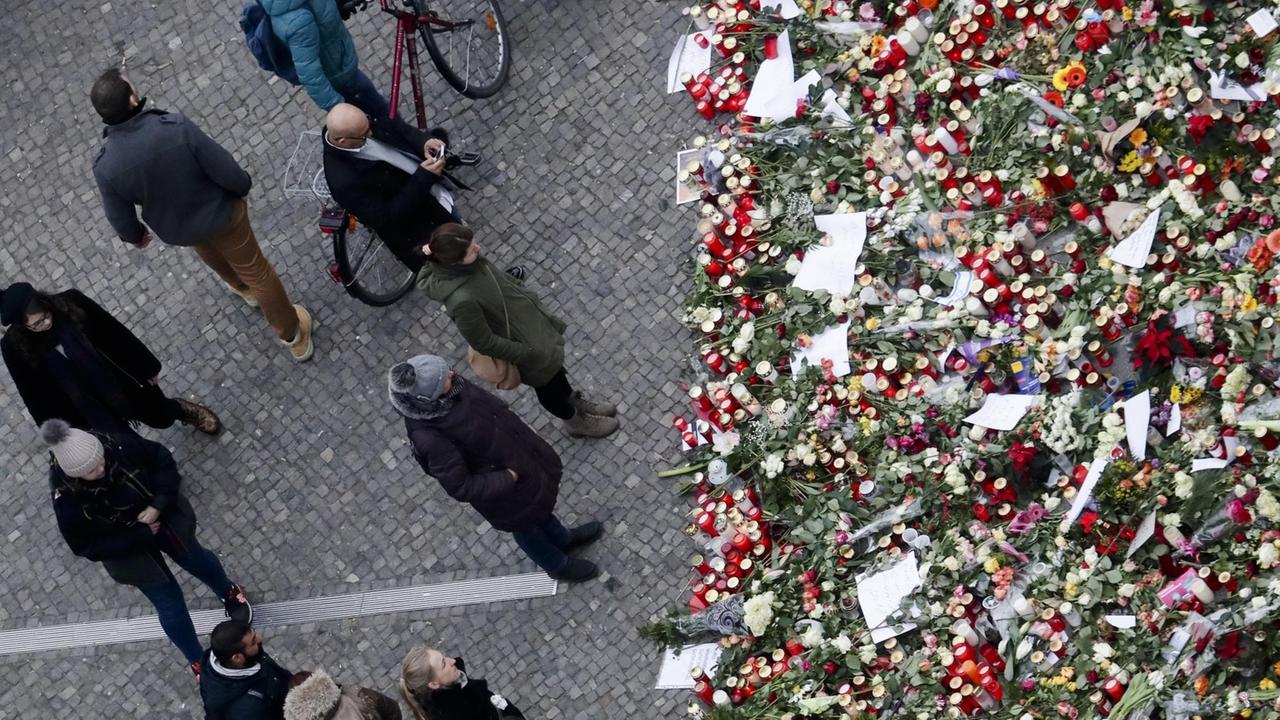 Menschen stehen an der Trauerstätte für die Opfer des Terroranschlags auf den Weihnachtsmarkt am Berliner Breitscheidplatz.