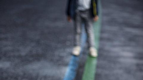 Ein Mensch steht auf einer asphaltierten Straße auf einer blauen und einer grünen Linie