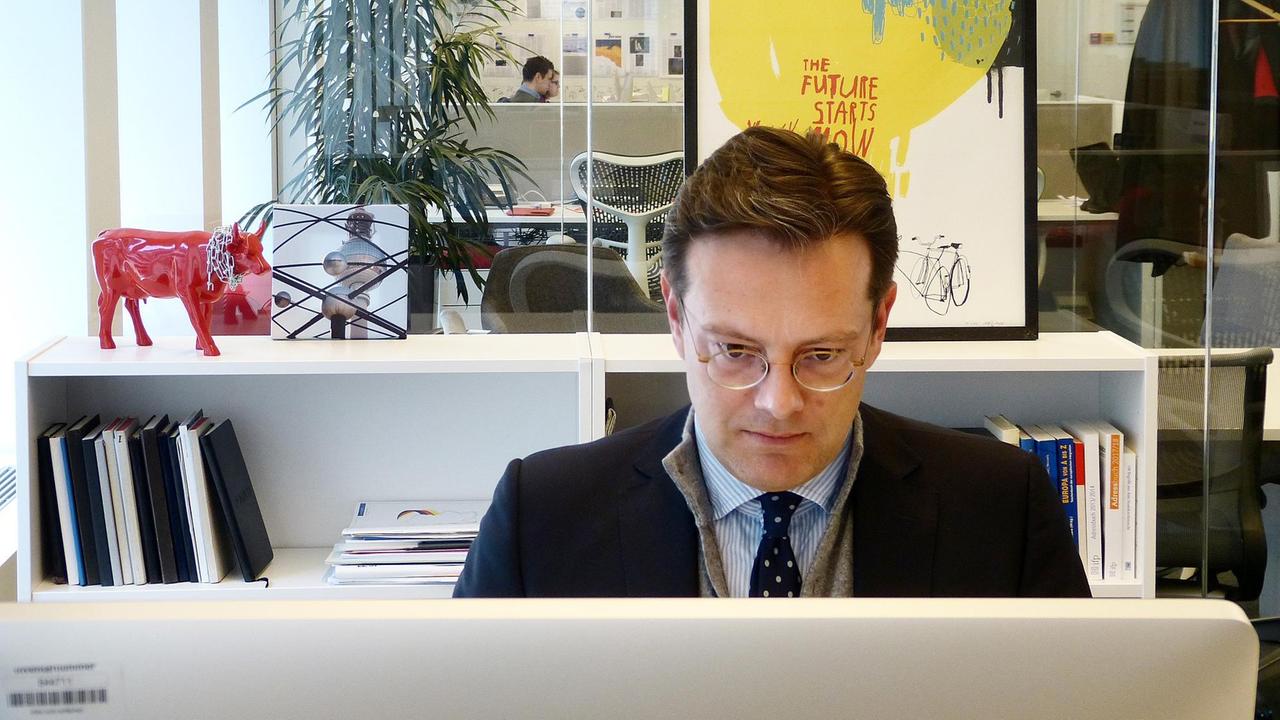Florian Eder sitzt an seinem Arbeitsplatz und schaut auf seinen Bildschirm