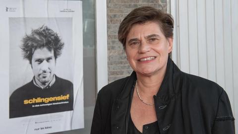 Bettina Böhler neben dem Plakat des Filmes "Schlingensief – In das Schweigen hineinschreien""