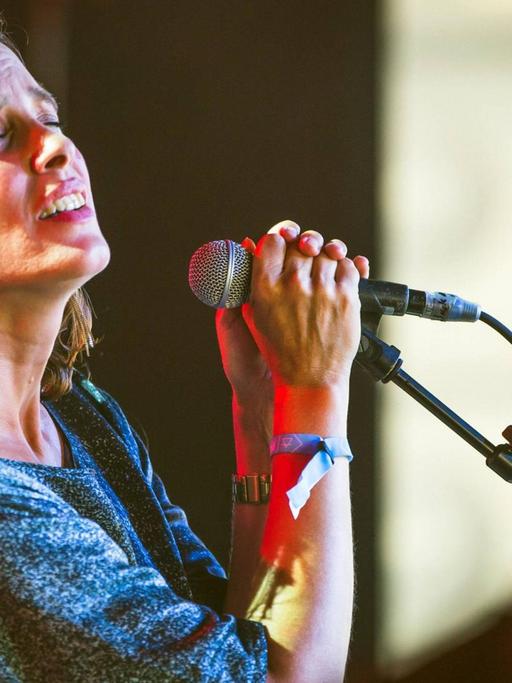 Elke Brauweiler steht auf der Bühne an einem Mikrofon und singt.