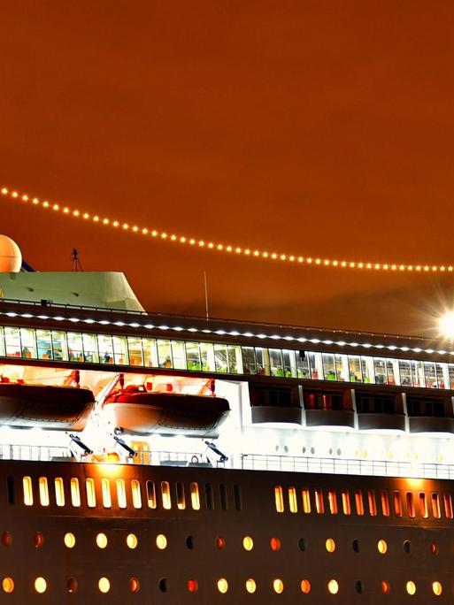 Ein Kreuzfahrtschiff mit seinen beleuchteten Decks (Symbolbild).