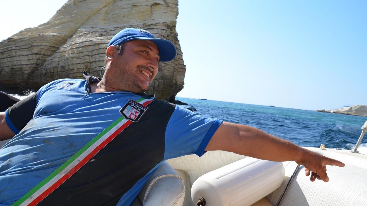 Der Fischer Ahmad Fawaz auf seinem Boot. Blaues Hemd und Basecap.
