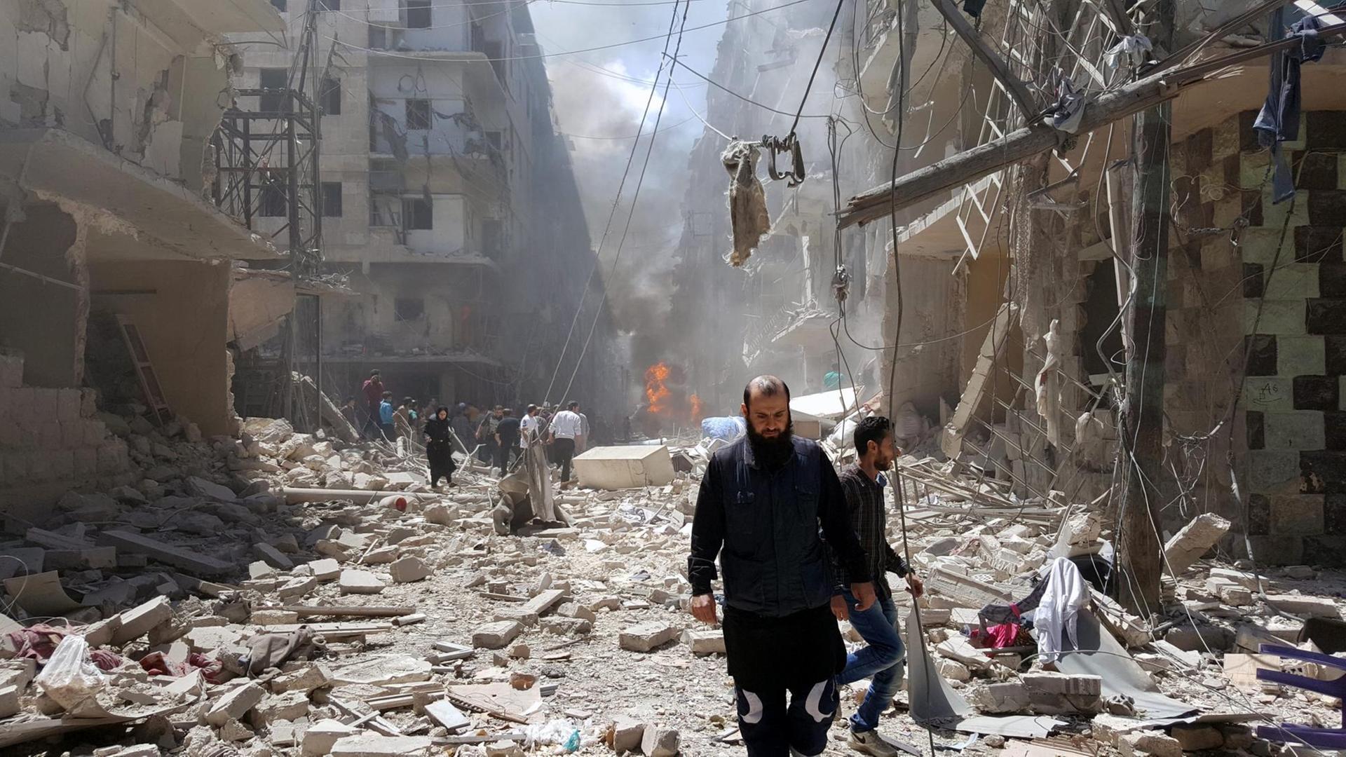 Der von Aufständischen kontrollierte Ostteil Aleppos wird durch Angriffe der syrischen Luftwaffe erschüttert. Sie sehen Syrer, die inmitten von Trümmern laufen.